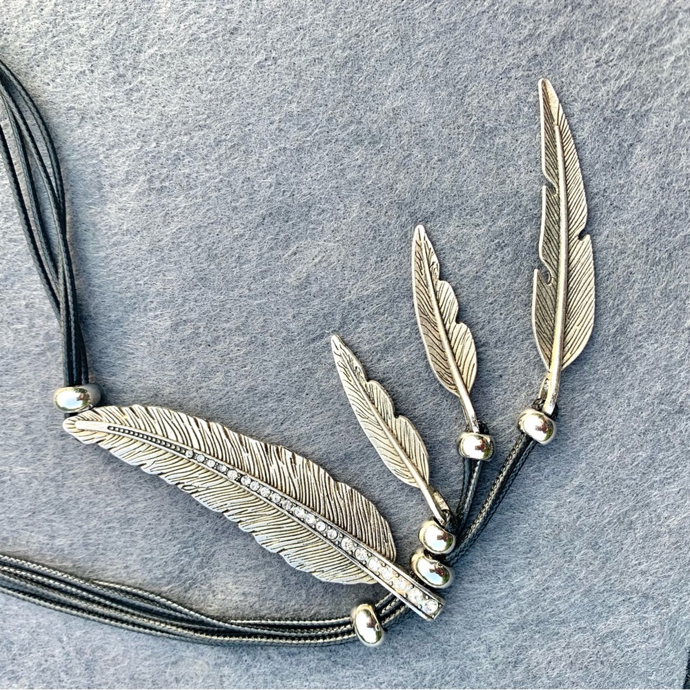 Main Feather slides to adjust look,silver toned feathers/black corded necklace.